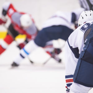 The hockey player is waiting for the puck to play.