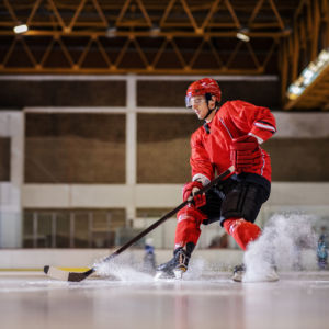 Full length of caucasian hockey player playing hockey on ice in hall.